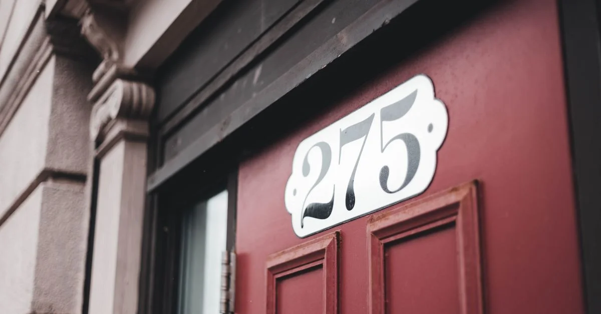 Gros plan sur une porte rouge avec un panneau décoratif numéro 275, architecture urbaine.
