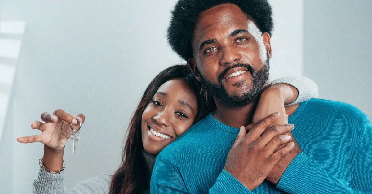 Couple joyeux tenant fièrement les clés de leur nouvelle maison, symbolisant de nouveaux départs.