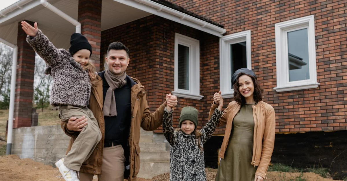 Une famille joyeuse célèbre l'achat de leur nouvelle maison avec des sourires et des vêtements chauds.