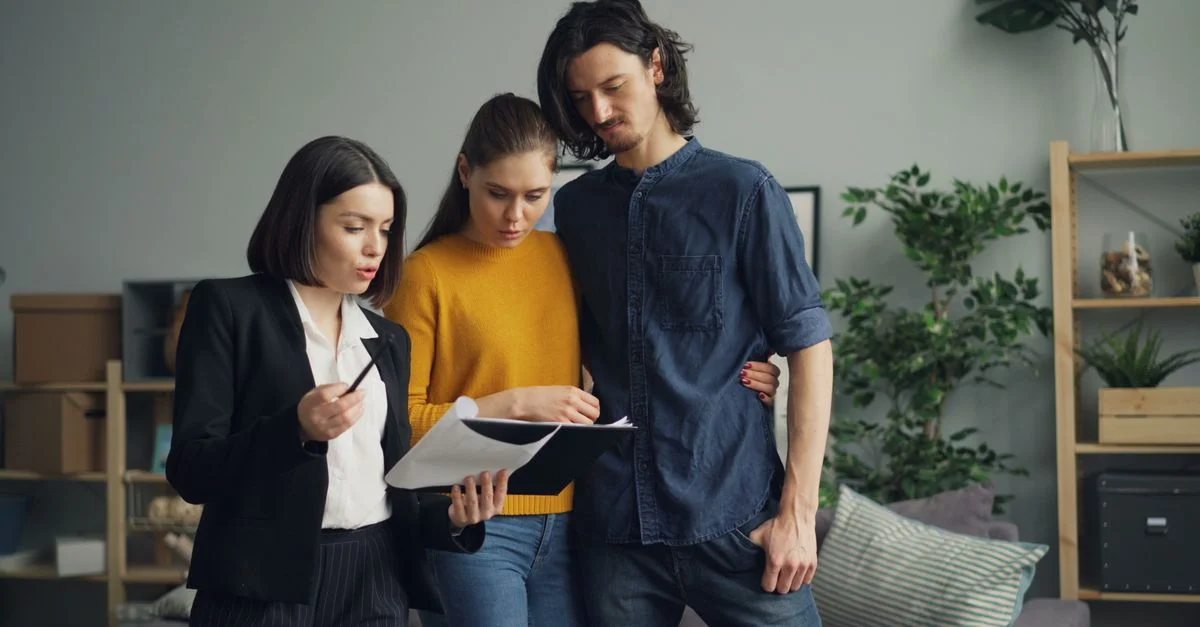 Un couple examinant des documents avec un agent immobilier à l'intérieur.
