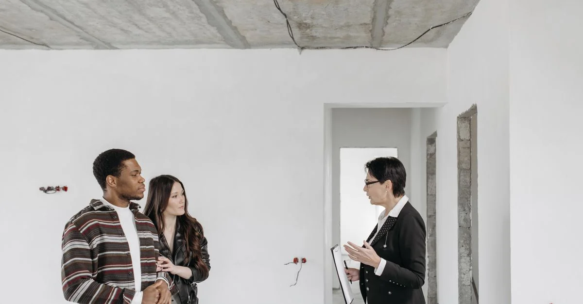 Agent immobilier discutant des détails de la propriété avec des clients dans un appartement inachevé.