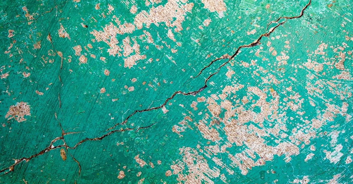 Gros plan d'un mur vert fissuré et texturé avec une surface qui pèle.