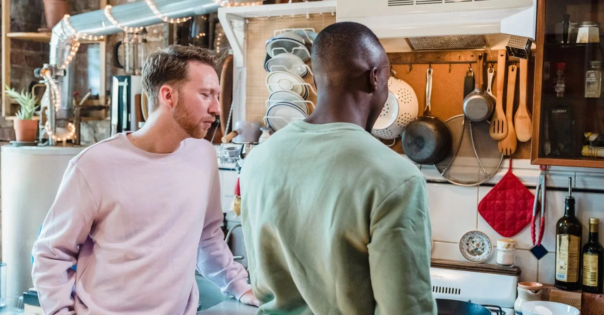 Deux hommes cuisinant dans une cuisine rustique et élégante, profitant d'un moment partagé.