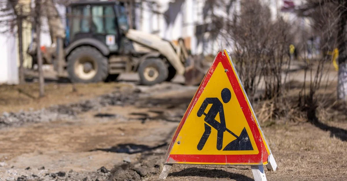 Un panneau de sécurité lumineux sur un chantier de construction routière avec des symboles de précaution visibles.