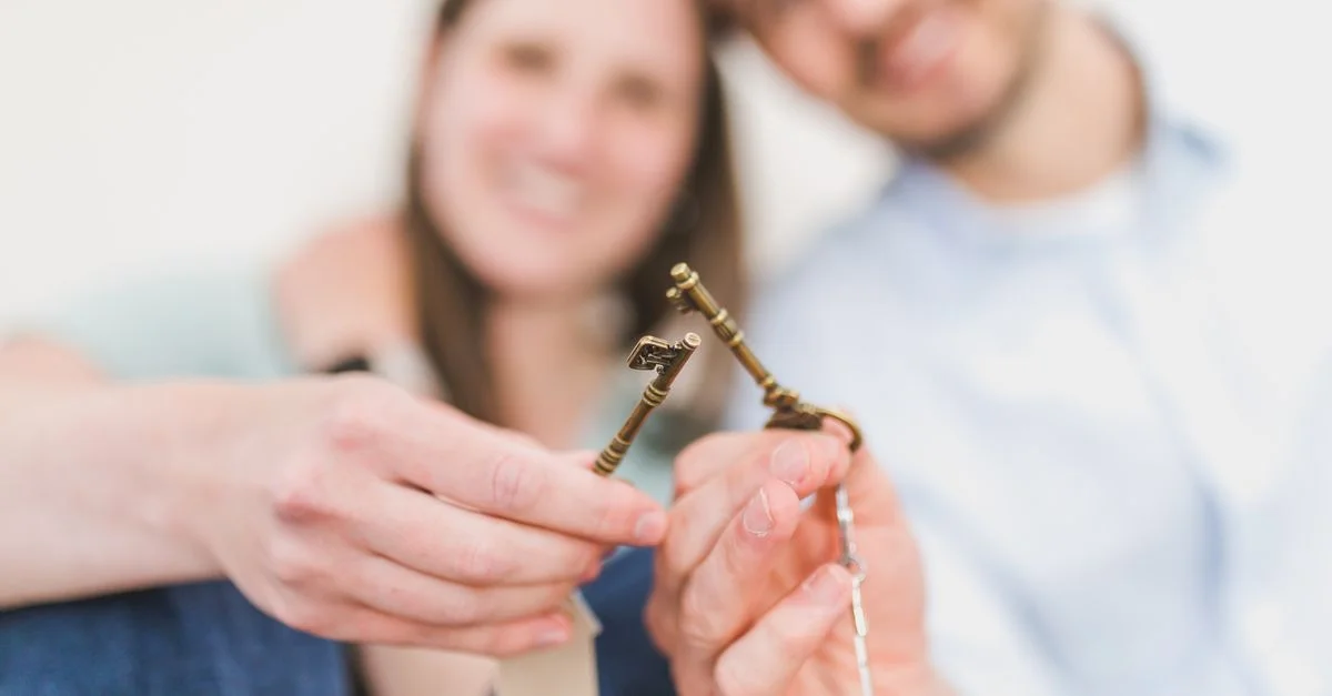 Un couple souriant célèbre l'achat de leur nouvelle maison, tenant des clés vintage avec amour et excitation.