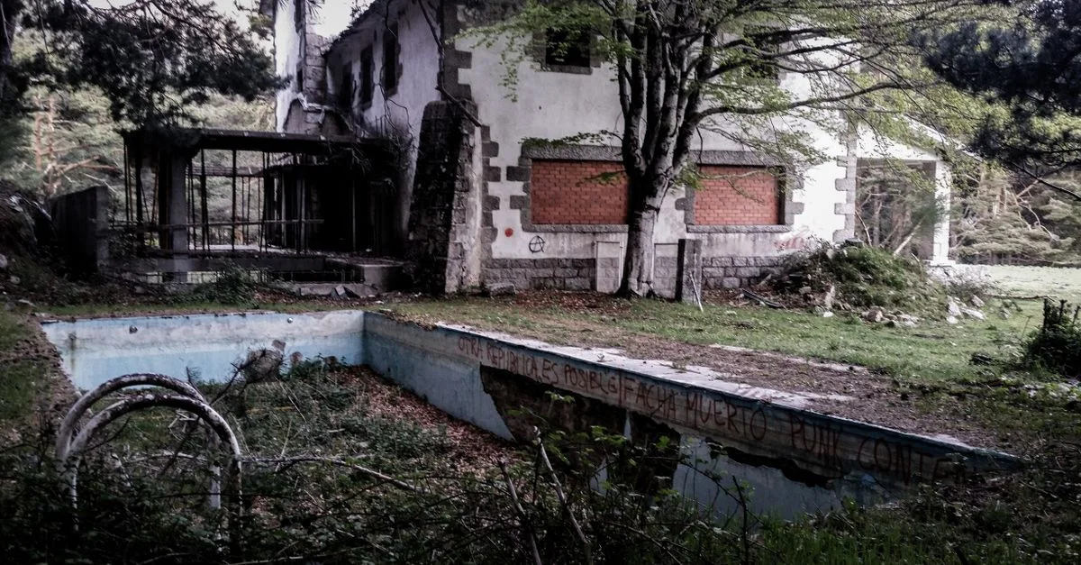 Maison en ruine avec une piscine envahie, entourée de forêt, symbolisant la décadence.